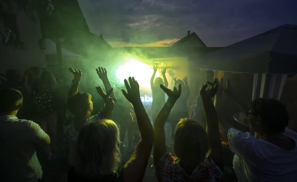 Tanzende Menge mit erhobenen Händen vor grünem Bühnenlicht beim Niklas Now Live-Event